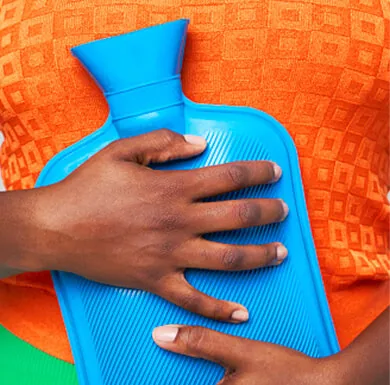 Hands holding a hot water bottle against stomach